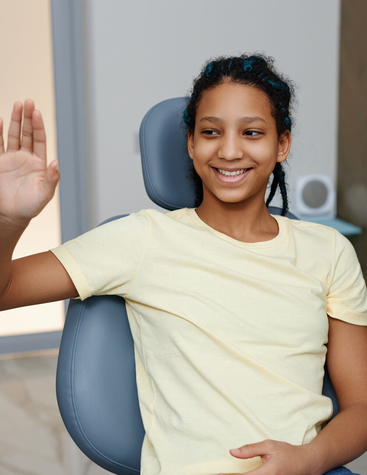 Portrait of teen black girl high-fiving dentist while enjoying dental care appointment in clinic and smiling