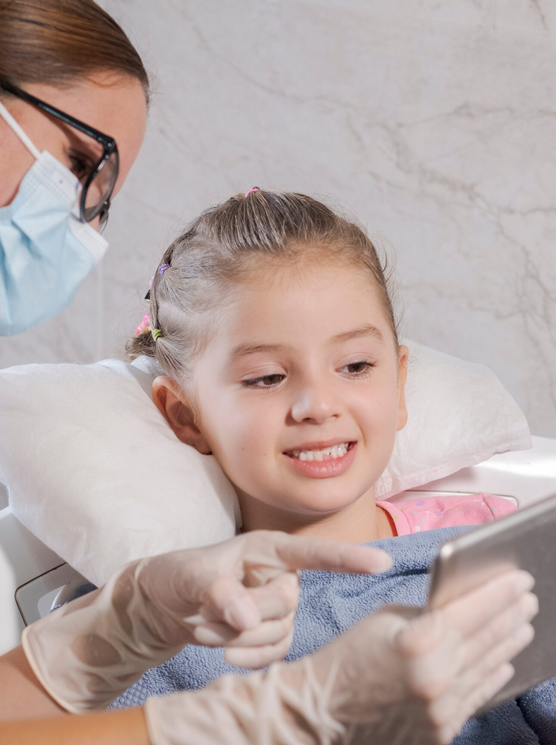 5 year old girl in pediatric dentistry office, the dentist is assisting her.