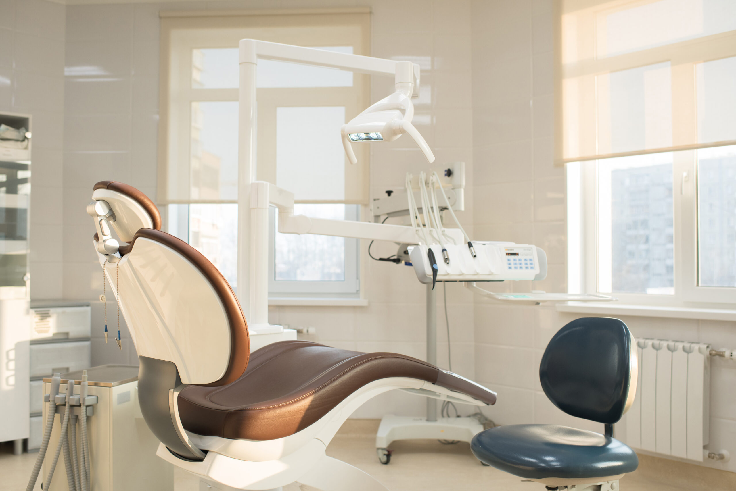 Nobody in clean modern dentists office: leather dental chair and operator stool, dental operating light, dental equipments for treatment