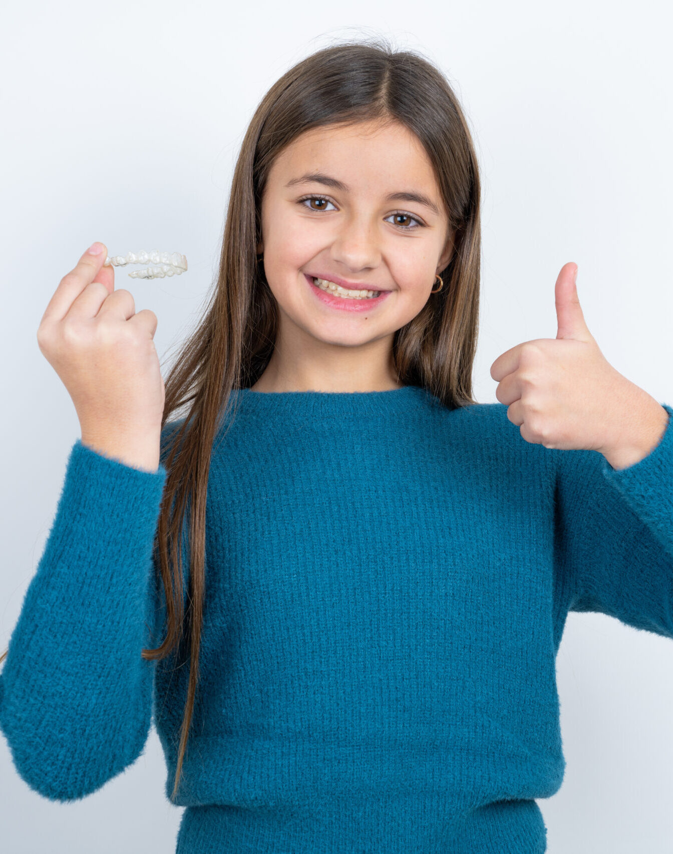 MODEL holding an invisible braces aligner and rising thumb up, recommending this new treatment. Dental healthcare concept.