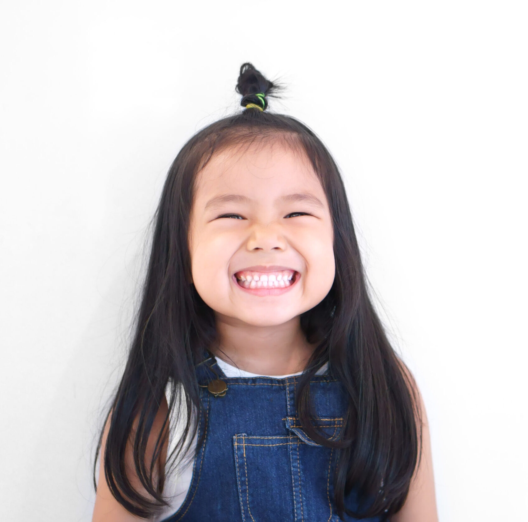 Asian children cute or kid girl and kindergarten student happy smile white teeth and laugh with wear dungarees jean for fashion on white background with space isolated