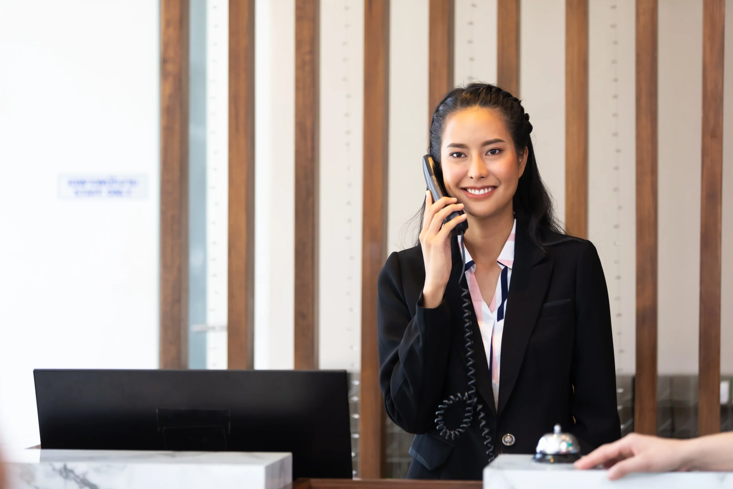Friendly receptionist woman working at desk in hotel lobby. Leisure and travel at holidays.