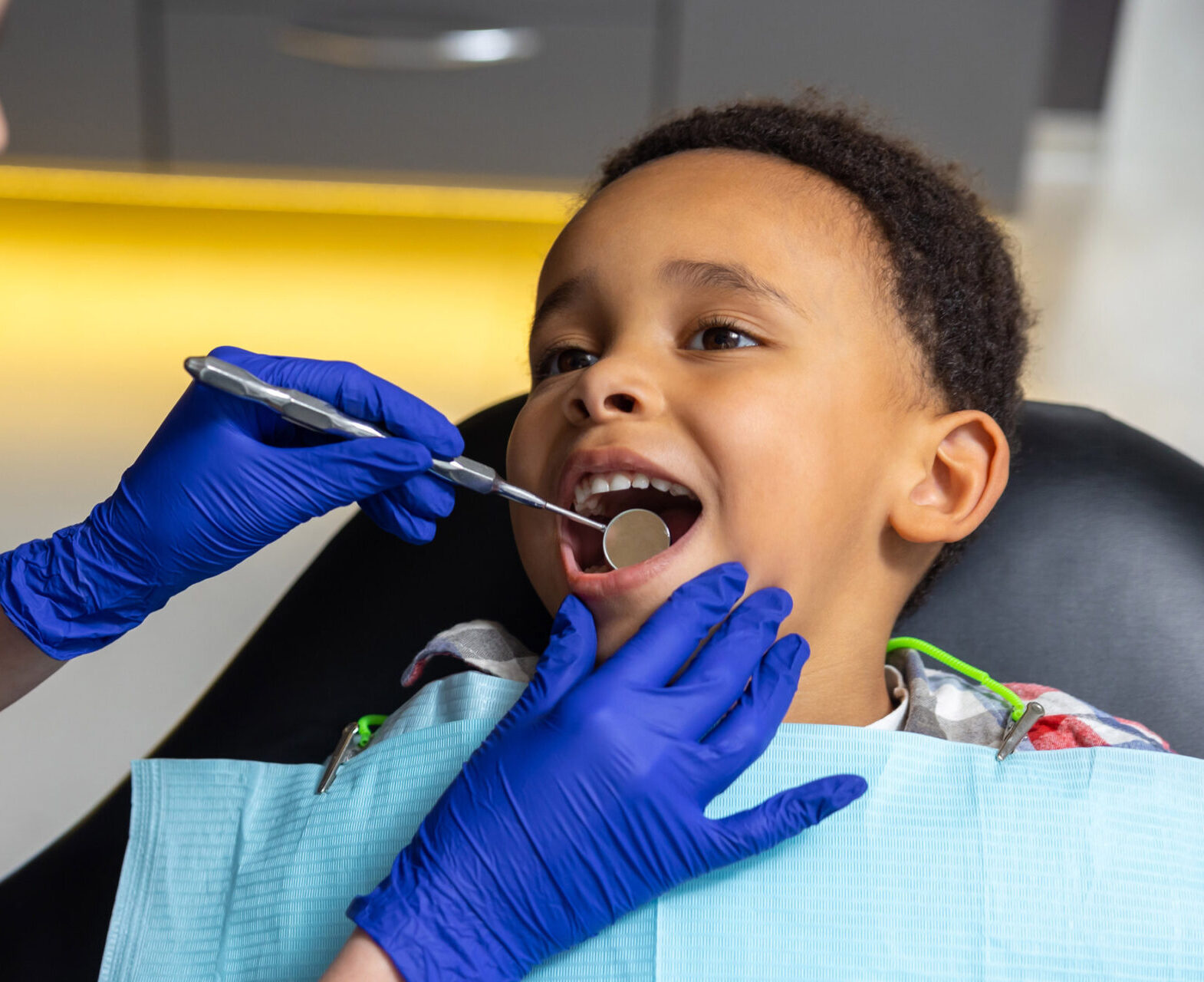 In dentistry. Female doctor checking up dark-skinned boy