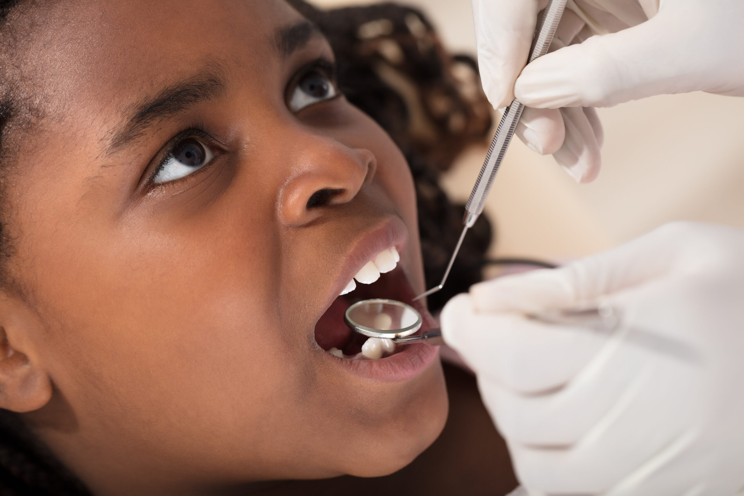 Dentist Examining A African Girls' Teeth In The Clinic