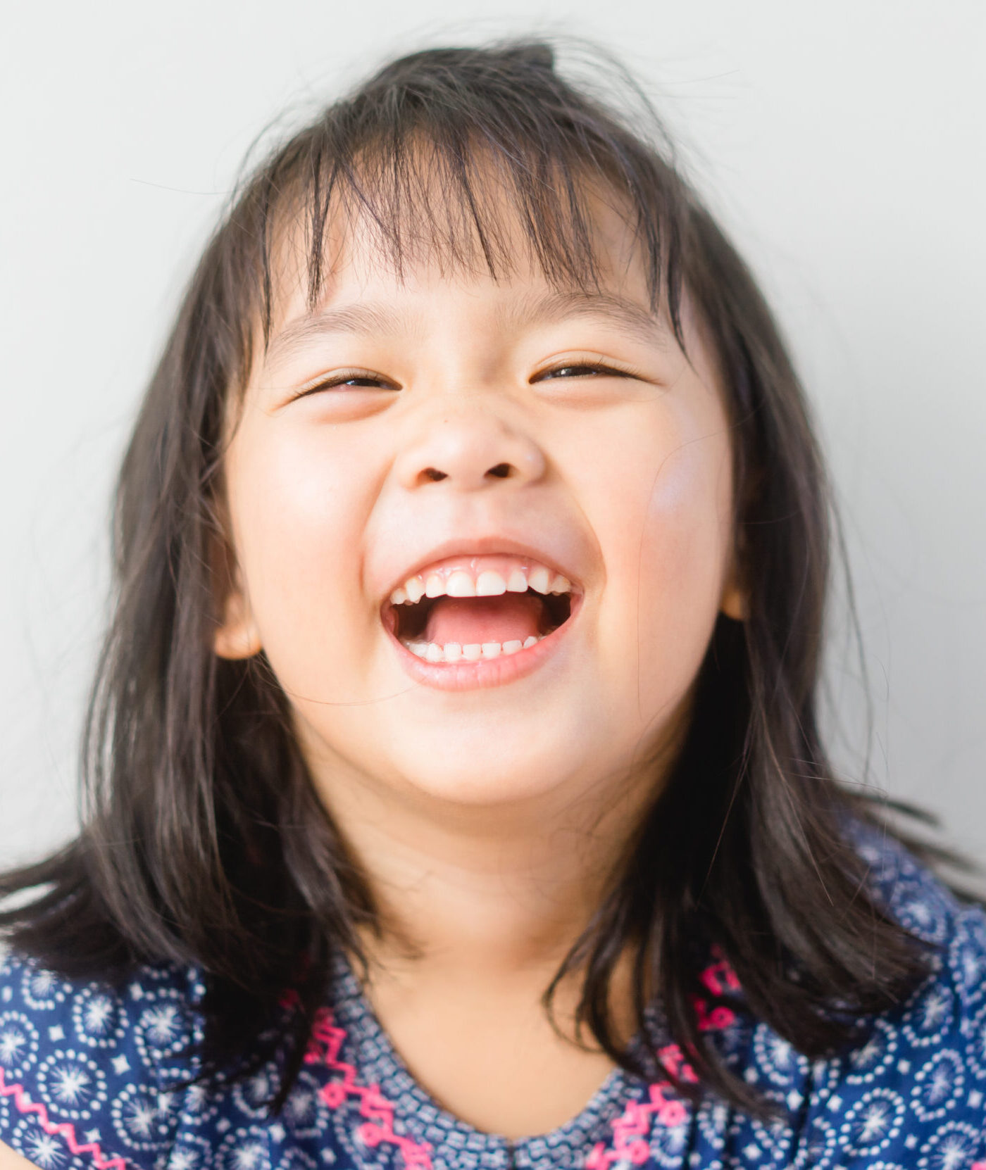 Happy Little asian girl child showing front teeth with big smile and laughing: Healthy happy funny smiling face young adorable lovely female kid.Joyful portrait of asian elementary school student.
