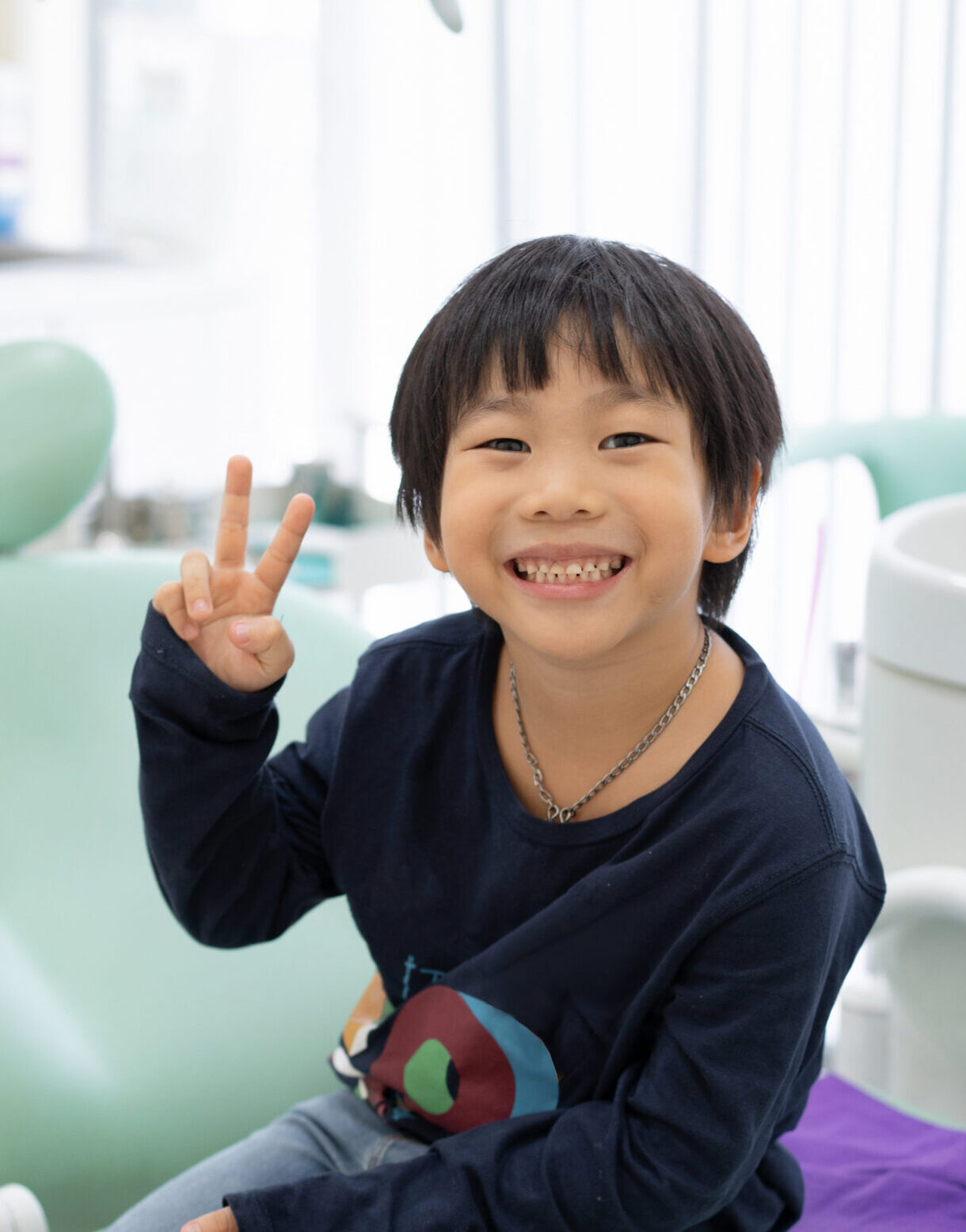 The Asian boy feel happy to sit on the dental chair in dental clinic