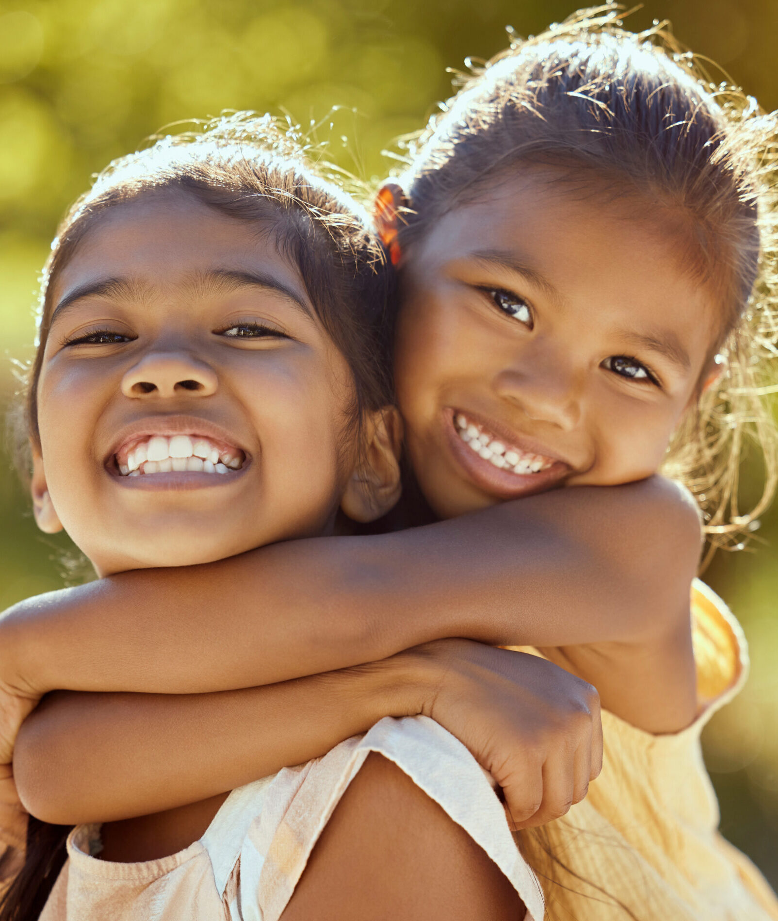 Girl, hug and love, sisters and happy in portrait together, young kids outdoor and family bonding in nature. Indian children smile, sibling relationship and care, spending quality time in park